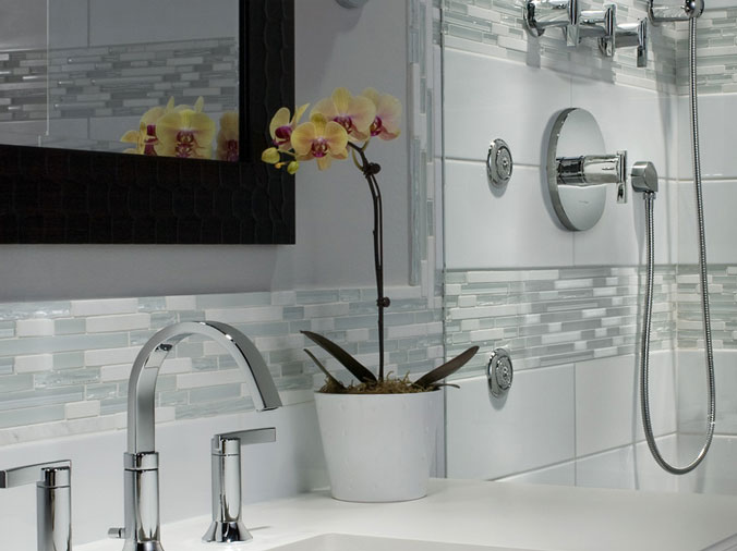 white bathroom with bathroom sink in foreground and shower with chrome fittings in the background