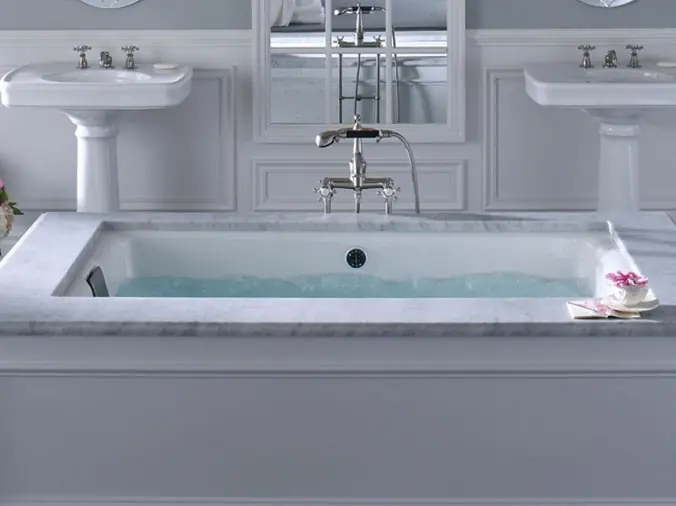 white free standing bathtub with two whiute pedustal bathroom sinks in the background